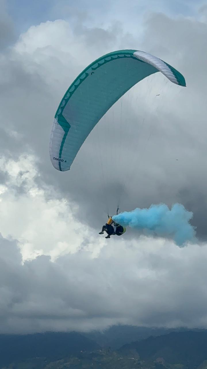 Parapente con humo azul de revelación de género entre las nubes