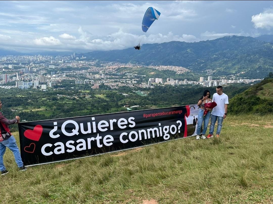 Propuesta de matrimonio con pancarta '¿Quieres casarte conmigo?' y parapente sobre Bucaramanga